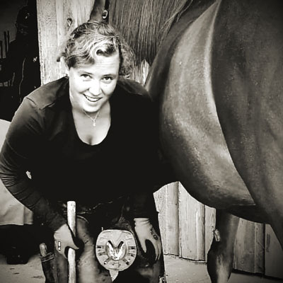 Hufschmiedin Anna, aus dem Team EquiBalance, mit Pferdehuf bereit zur Bearbeitung